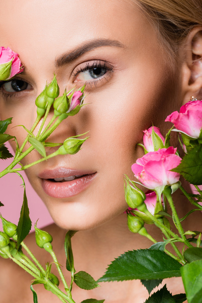 beautiful blonde woman in rose flowers isolated on pink - Photo, Image
