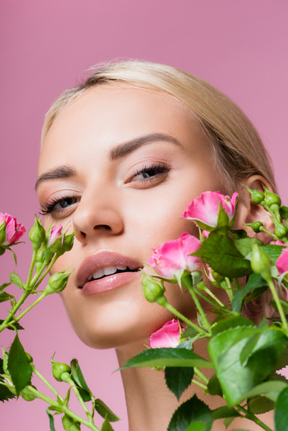 όμορφη ξανθιά γυναίκα σε τριαντάφυλλο λουλούδια απομονωμένη σε ροζ - Φωτογραφία, εικόνα