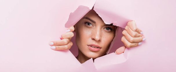 beautiful woman with freckles in pink paper hole, banner - Photo, Image