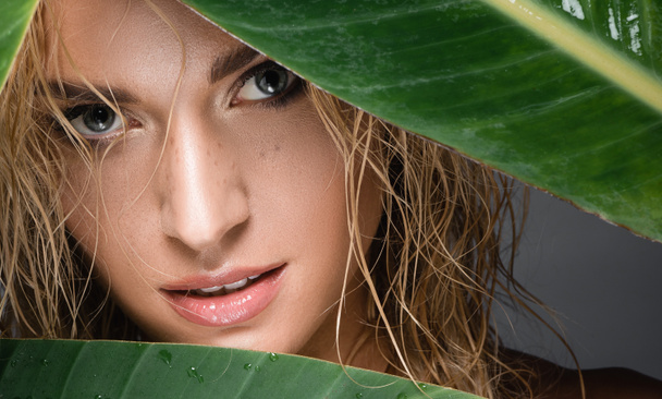 blonde woman with wet hair and green leaf - Fotoğraf, Görsel