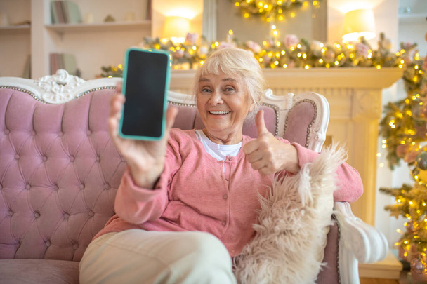 Senior woman showing her smartphone and looking contented - Foto, Bild