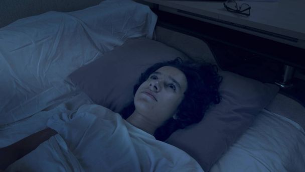 teenage boy suffering from insomnia lying in bed at night - Valokuva, kuva