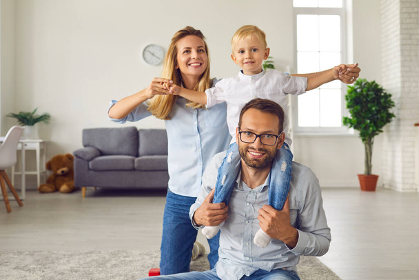 Happy young family spending time together in living room of their new studio apartment - Fotoğraf, Görsel