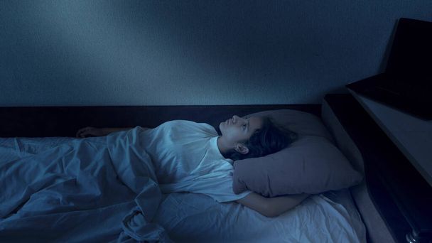 portrait of a teenage girl suffering from insomnia lying in bed at night - Foto, Imagen