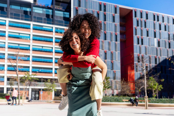 Female couple piggybacking and having great time in the city. - 写真・画像
