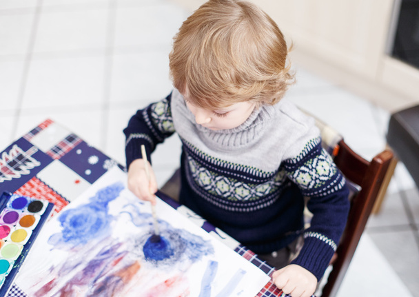Lindo niño divirtiéndose en interiores, pintando con diferente dolor
 - Foto, Imagen