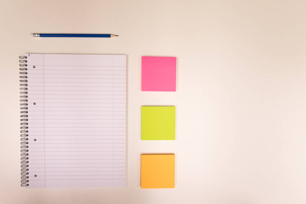 Bloco de notas, lápis e pequenas notas coloridas numa secretária branca - Foto, Imagem