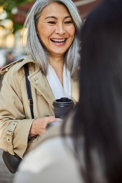 Cheerful woman talking with friend on the street - Fotoğraf, Görsel