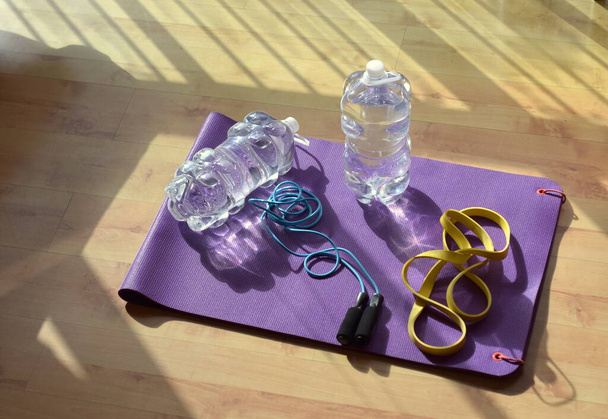 Training at home because of covid, jugs of water, purple mat and yellow rubber - Photo, Image
