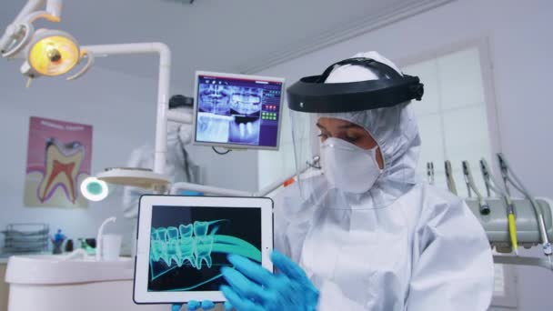 Medico che mostra radiografia digitale su tablet in studio dentistico con nuovo normale - Filmati, video