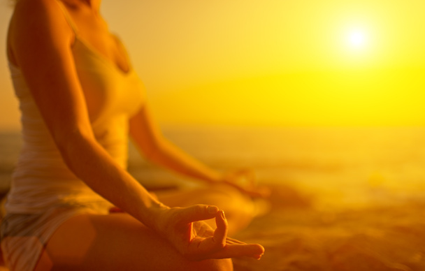 hand of  woman meditating in a yoga pose on beach at sunset - Photo, Image