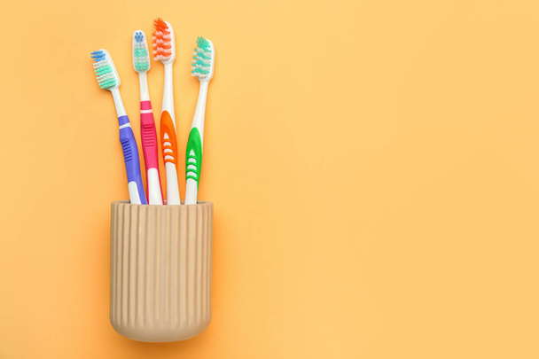 Cup with tooth brushes on color background - Photo, Image