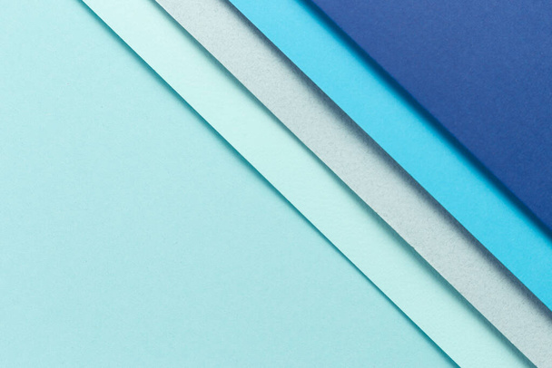 Material Design blauer Hintergrund. Bastelpapierbögen werden auf unterschiedliche Weise gefaltet. Ein Foto - Foto, Bild