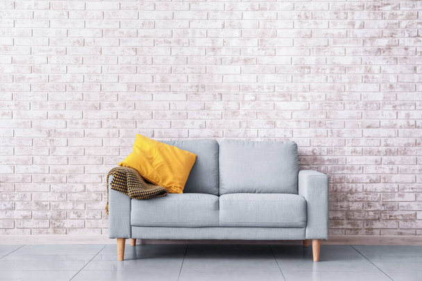 Stylish sofa near brick wall in room - Foto, Imagen