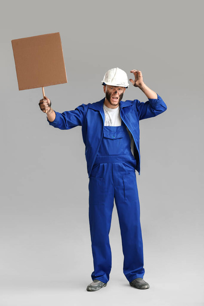 Protesting miner man with placard on grey background - Foto, Imagen