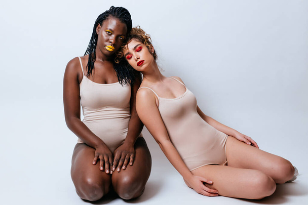 Two girls from different ethnicities posing in studio for a "body positivity" photo session - 写真・画像