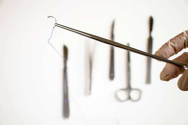 Műtét felszerelés, kés, tű és varrat. Stúdió fotózás a fehér háttér. - Fotó, kép