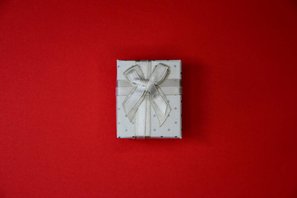 White box with bow on the red background, Christmas gift isolated - Фото, зображення