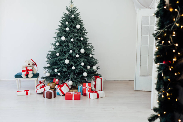 Újévi karácsonyfa ajándékokkal és díszítő koszorúkkal belső tér - Fotó, kép