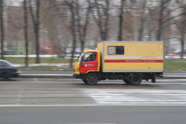 Moskwa, Rosja, 20 listopada 2020 r.: czerwony i żółty samochód z napisem "Pogotowie ratunkowe" jedzie po drodze pod śniegiem, w ruchu - Zdjęcie, obraz