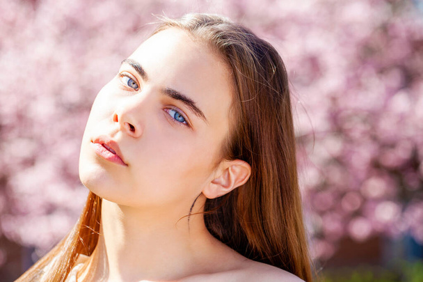 Beauty teen girl posing near blossom cherry tree with pink flowers. Spring park - Foto, immagini