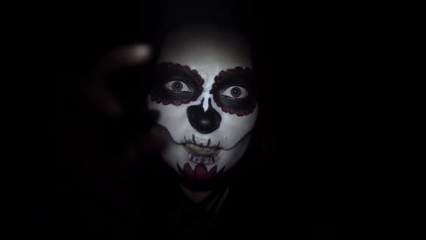 Een dame met een mystieke make-up in santa muerte stijl op zwarte achtergrond in close-up - Video