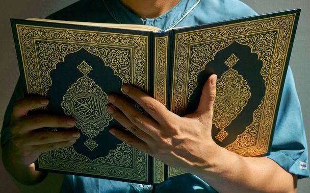 Hombre musulmán no identificado con camisa azul leyendo el Corán - Foto, imagen