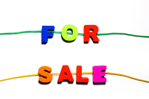 Na prodej slovní text napsaný z dřevěných barevných abecedních písmen s otvory, navlečený na krajce, nakupování, koncept prodeje  - Fotografie, Obrázek