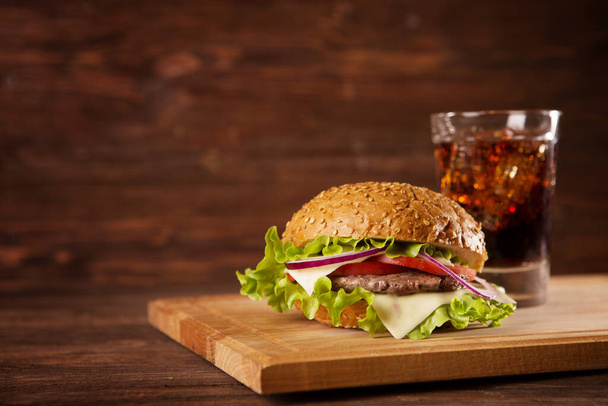Zwei Hamburger und Cola auf dem Tisch vor dunklem Hintergrund. Leckeres Fast Food. - Foto, Bild