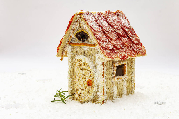 Şarküteri köşkü ya da Noel 'in en yeni yemek modası olarak Et Kulübesi. Geleneksel dekoru ve sembolleri olan yeni yıl keto kurabiyesi evi. Beyaz kar arkaplanı, kopyalama alanı - Fotoğraf, Görsel