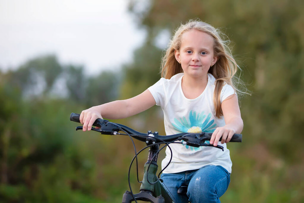 A girl with long hair rides a bicycle on a summer day. - Photo, Image