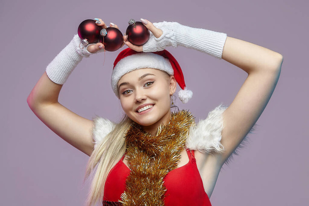 beautiful young woman in Santa costume holding Christmas ornaments - Фото, зображення