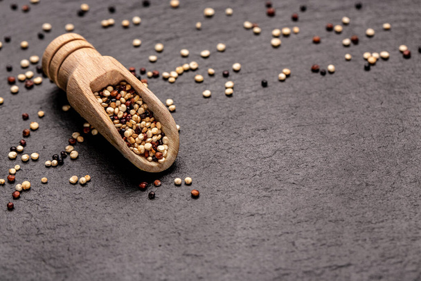 rohe, unbehandelte Quinoa-Samen in einer Holzschaufel auf Steingrund gemischt. Superfood-Produkt. Banner, Menü, Rezept, Platz für Text. Ansicht von oben, - Foto, Bild