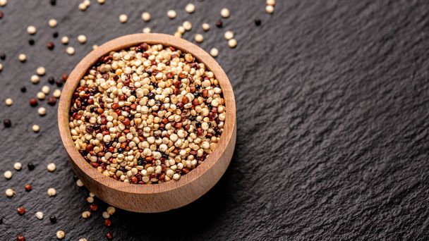 Quinoa-Samen in Holzschale auf Steingrund. Diät Superfood-Produkt. Banner, Menü, Rezept, Platz für Text. Ansicht von oben. - Foto, Bild