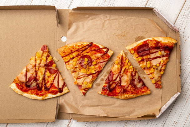 Pizza in a cardboard box on a white wooden background. - Zdjęcie, obraz