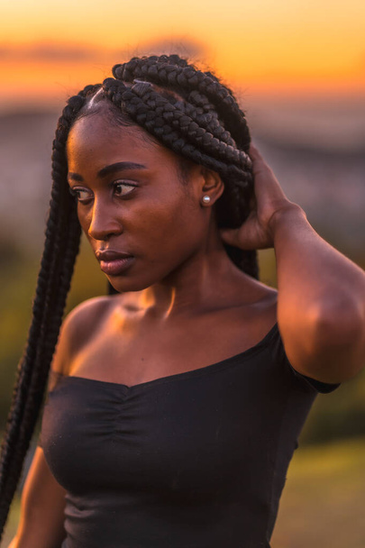 Lifestyle, Latina girl with black skin in a tight black short dress. Portrait of the young man on top of the mountain in a beautiful summer sunset - Foto, Bild