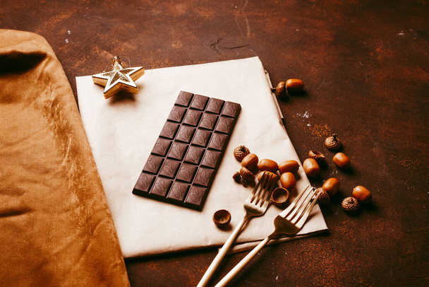 chocolate bar on a dark brown background on a piece of paper - Zdjęcie, obraz