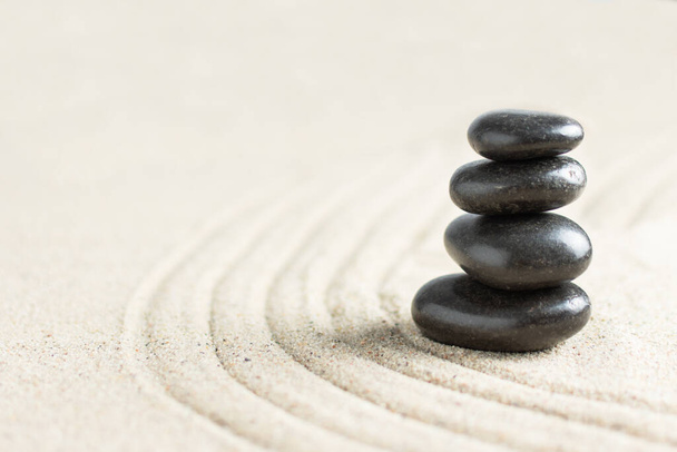 Fekete zen kövek egy halom tengerparti homokban. Meditációs kő háttér. Relaxációs egyensúly vagy spa kezelési koncepció. - Fotó, kép