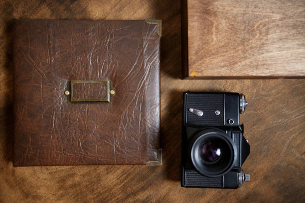 Cadeaufotoboek in een leren omslag in een houten doos op een beboste achtergrond. Vintage fotoalbum. Semeinfe foto 's van het leven van één persoon. - Foto, afbeelding