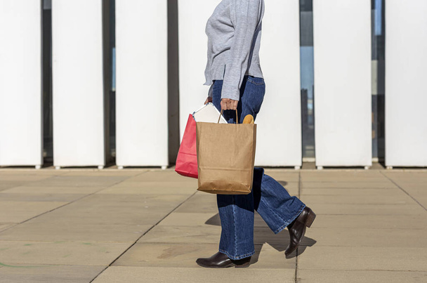 Mujer irreconocible llevando papel reciclable llevar bolsa de comida - Foto, Imagen