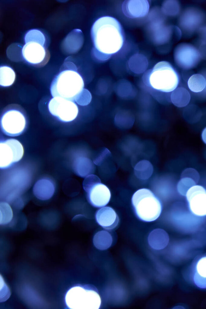 冷たい青い色。黒を背景に白と青の光のボケを強調。ブラー抽象的なブルーの輝きのテクスチャ。ぼかしボケ｜クリスマス、新年や祭りの背景のためのグリッター壁紙.  - 写真・画像
