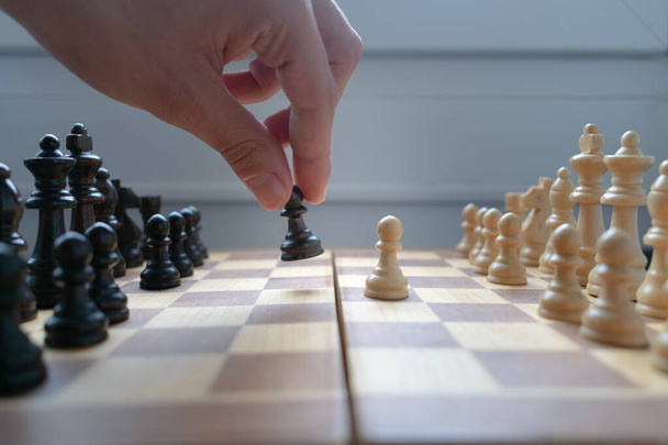 A hand is moving a black pawn, after the white side started the game. strategy game, intelligence and strategy concepts - 写真・画像