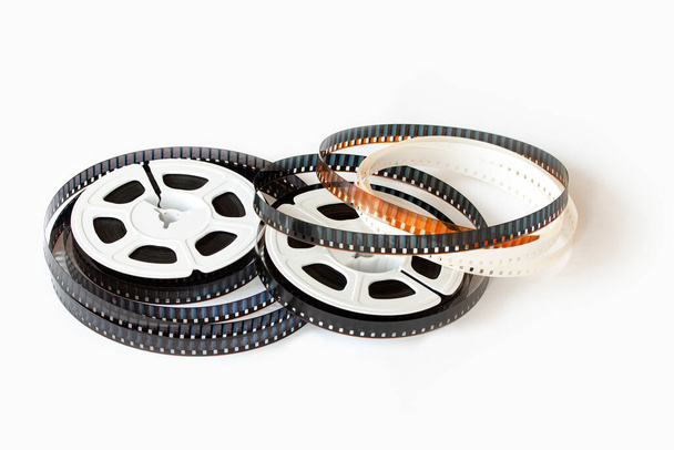 Due bobine di film da 8 mm con strisce di film sparse in giro. Colpo in studio. Immagine ravvicinata isolata su sfondo bianco. - Foto, immagini