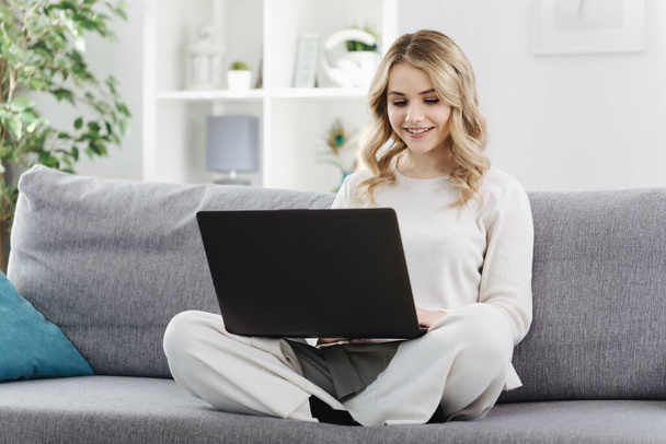 Female surfing internet on laptop at home - 写真・画像