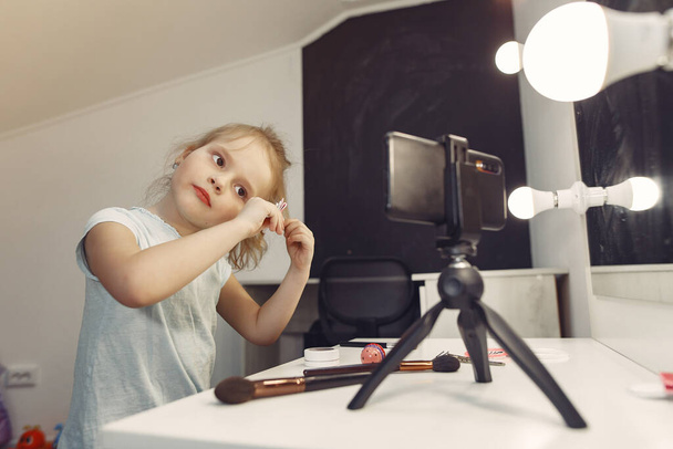 Cute little blogger with cosmetics recording video at home - Fotó, kép
