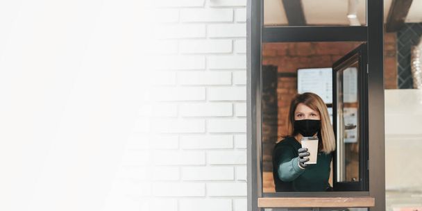 Masked barista spills coffee through the window because of coronavirus - Valokuva, kuva