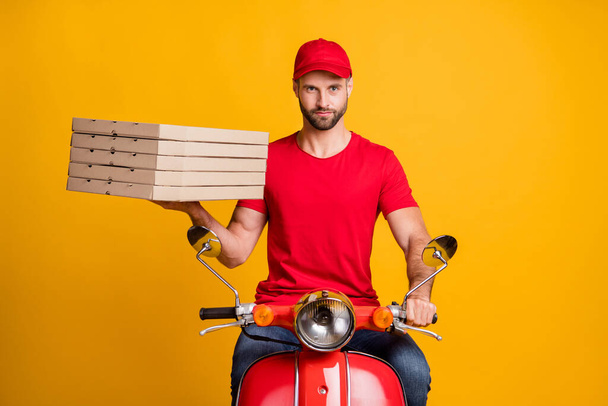 Photo of bearded guy ride motorbike hold carton pizza boxes wear red t-shirt cap isolated yellow color background - Fotó, kép
