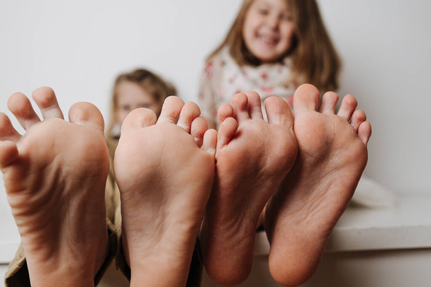 Childrens feet close up to the camera. Their blurred faces in a background. - Фото, изображение