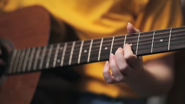 De hand van een vrouw klemt de frets op de gitaar. Handen van dichtbij. Gitaarleren spelen. - Video