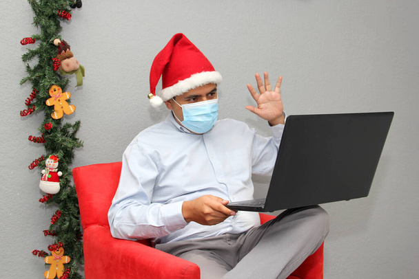 uomo latino con maschera di protezione, cappello di Babbo Natale e laptop in videoconferenza, decorazione natalizia, nuovo covid-19 normale - Foto, immagini